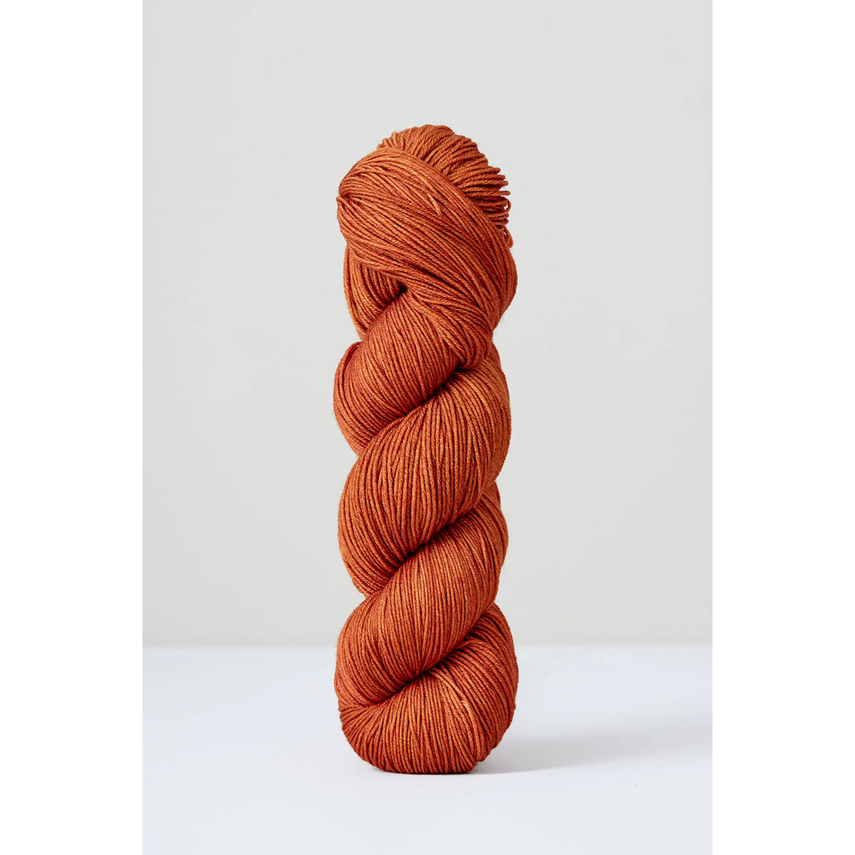 A skein of Urth Harvest Fingering Cinnamon, a warm ochre brown color.