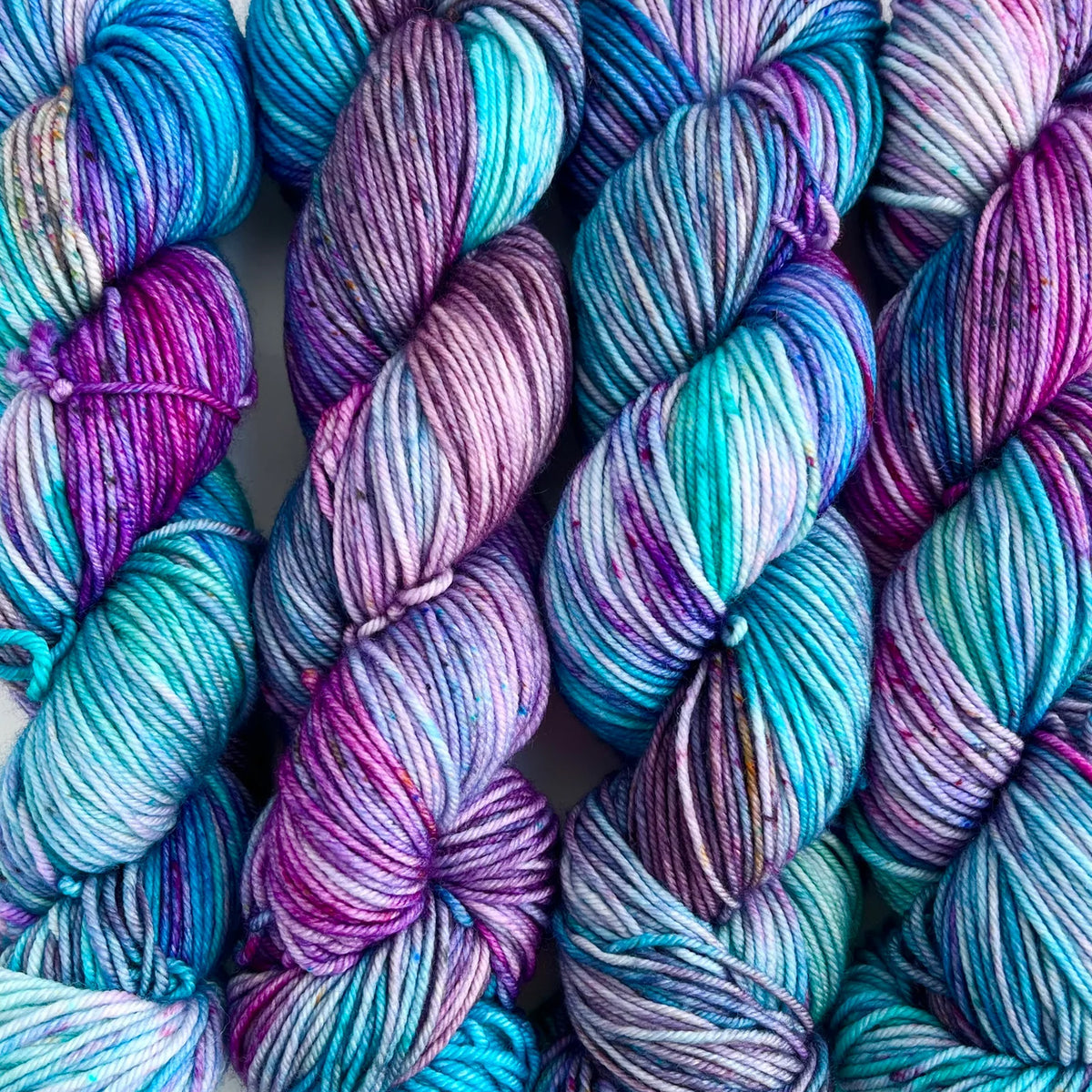 Skeins of Tributary Tidal DK Clear Creek, variegated shades of purple and turquoise 