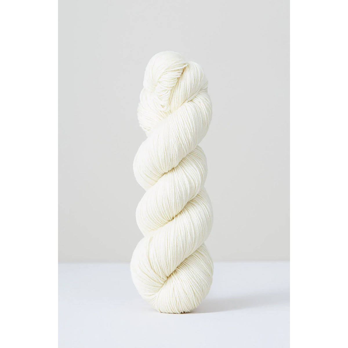 A skein of Urth Harvest Fingering Ecru, a creamy off-white color.