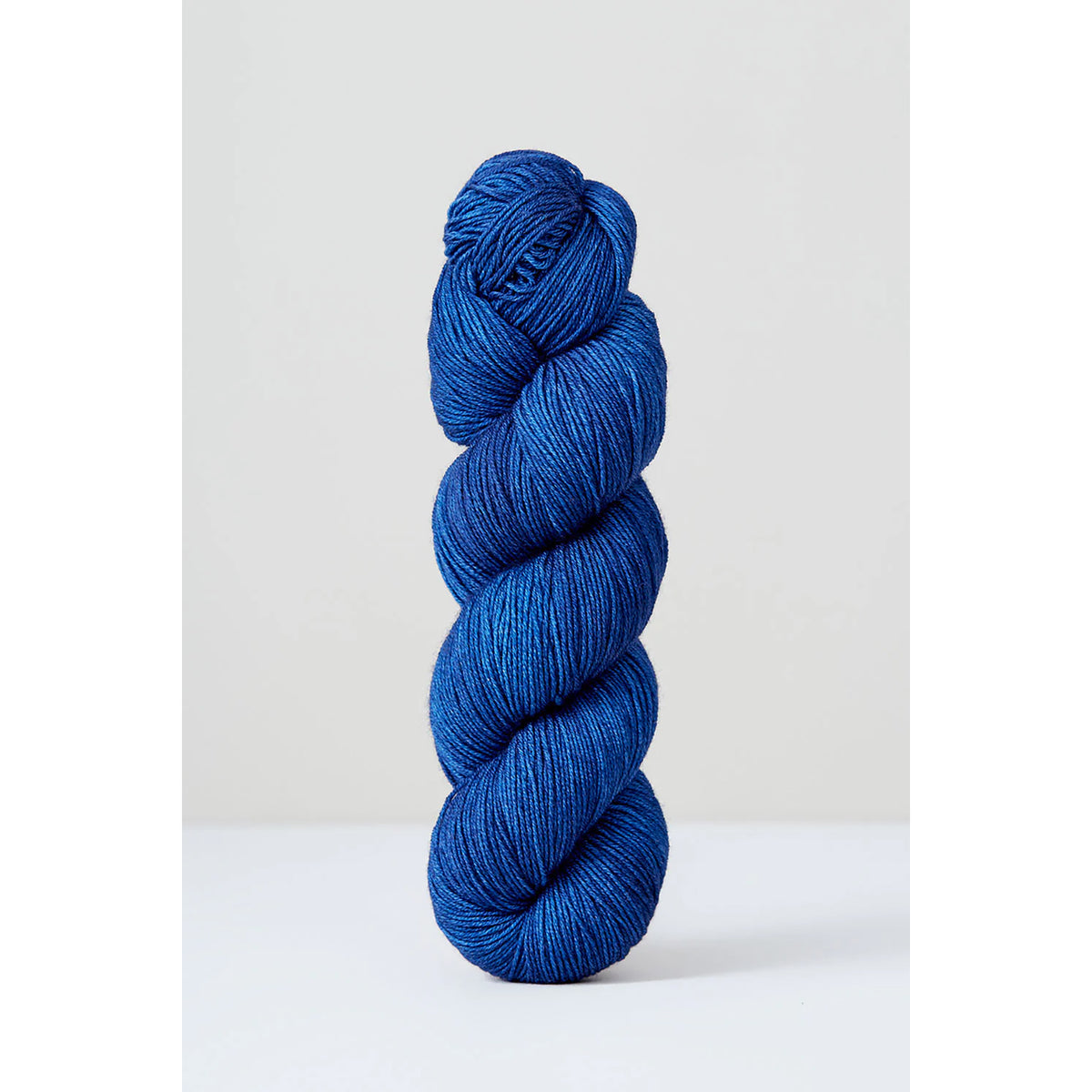 A skein of Urth Harvest Fingering Indigo, a rich ocean blue color.