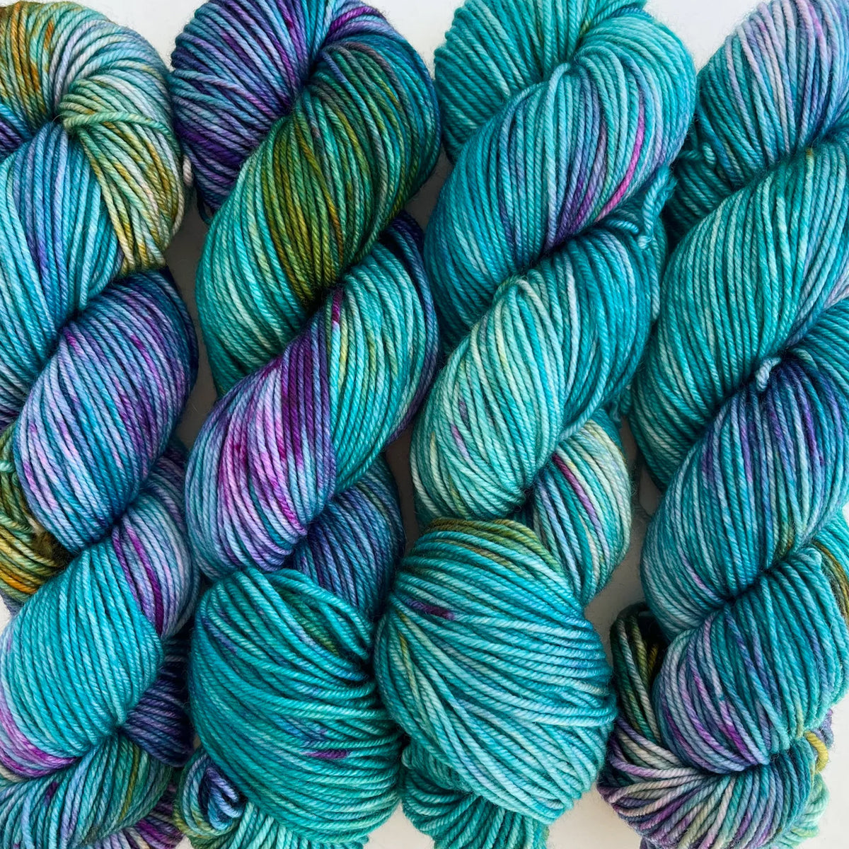 Skeins of Tributary Tidal DK Knitopia, variegated aqua blue, purple, and green