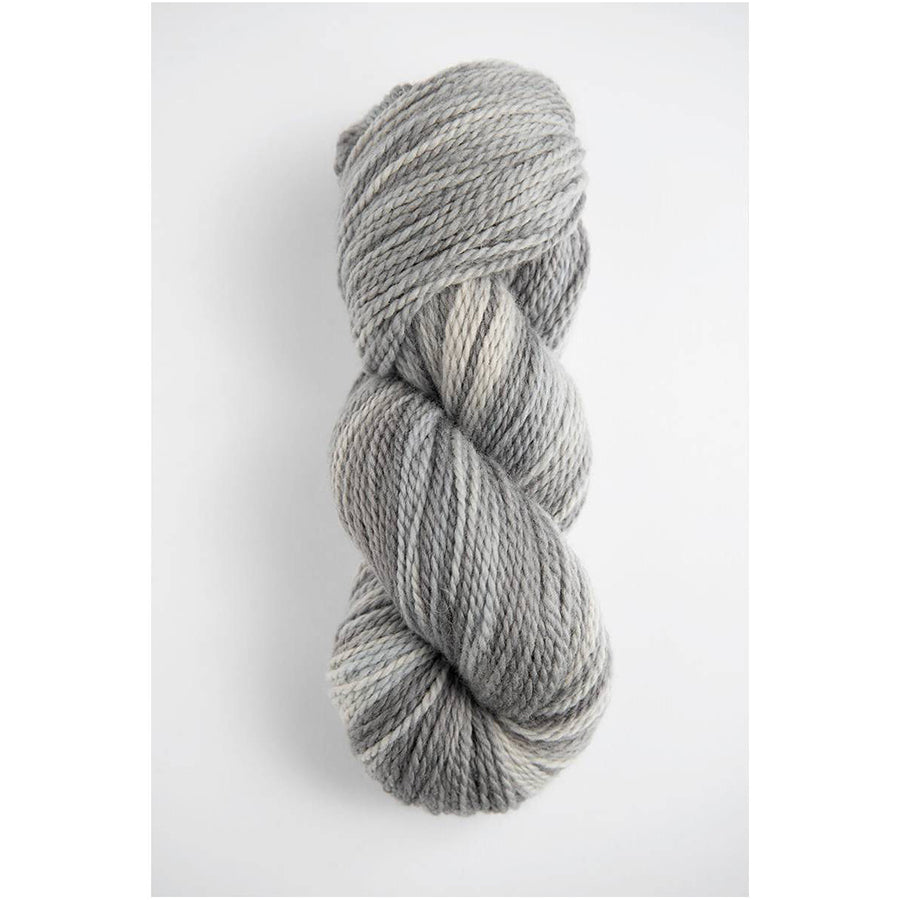 A skein of Amano Riti Mist in variegated light greys and white