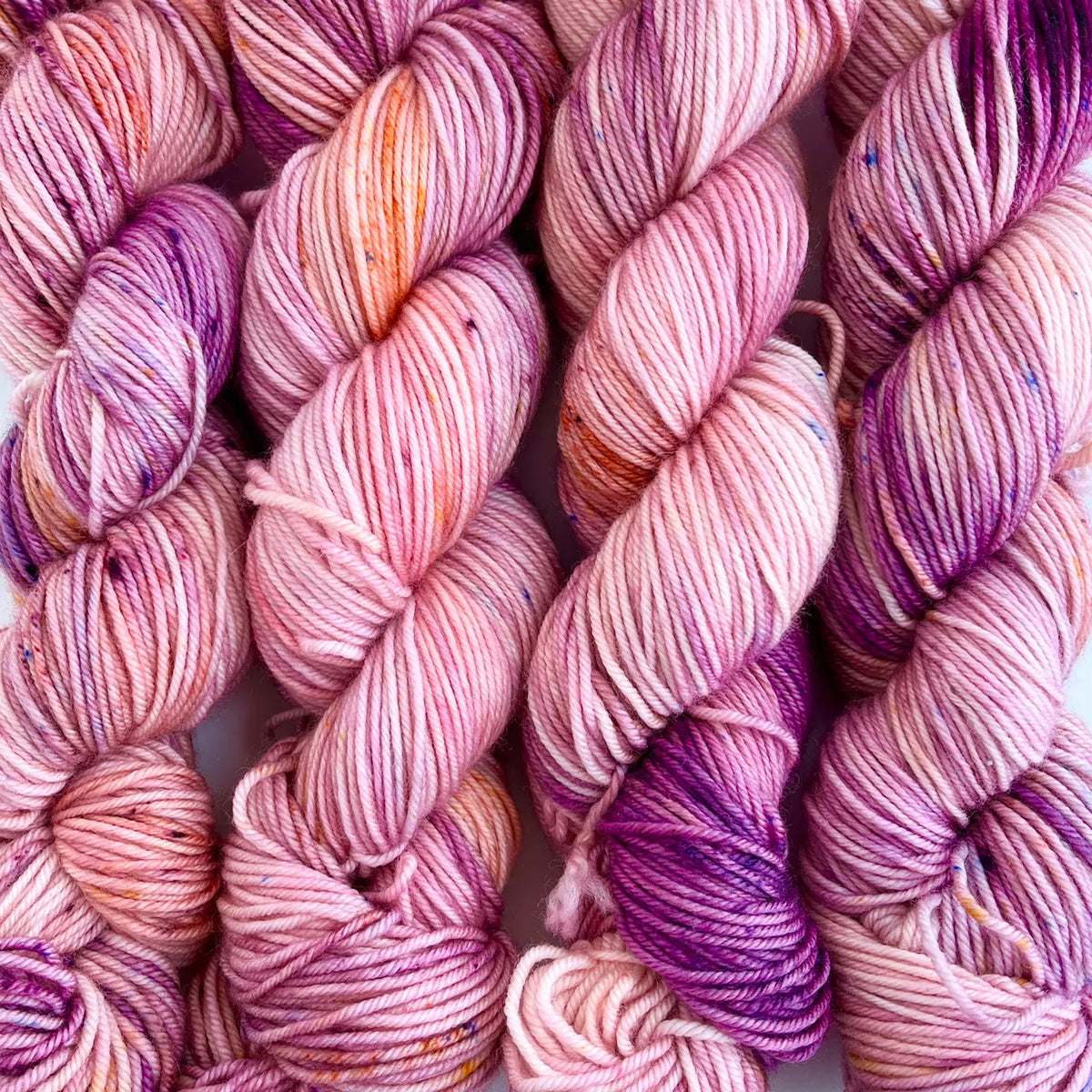 Skeins of Tributary Tidal DK Orchard, variegated light pink, orange, and purple