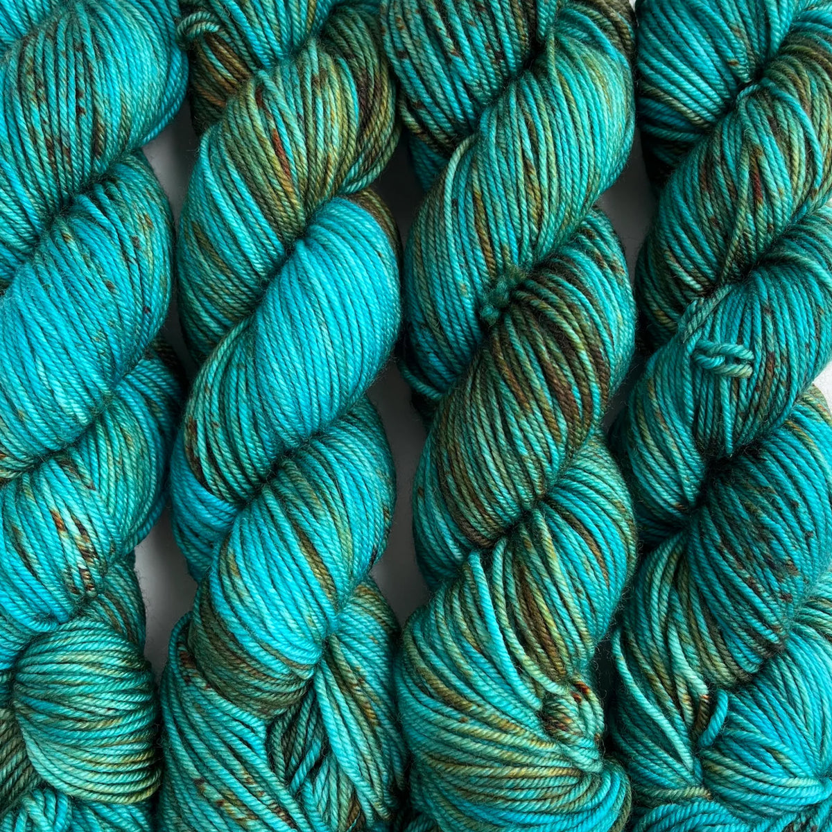 Skeins of Tributary Tidal DK Sunnis Favorite, variegated turquoise with olive green and rust orange