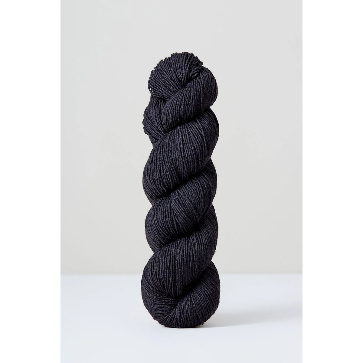 A skein of Urth Harvest Fingering Thuja, a deep black color.