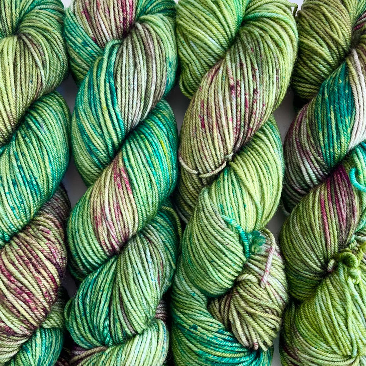 Skeins of Tributary Tidal DK Ryan Creek, variegated shades of green with hints of teal and dark magenta