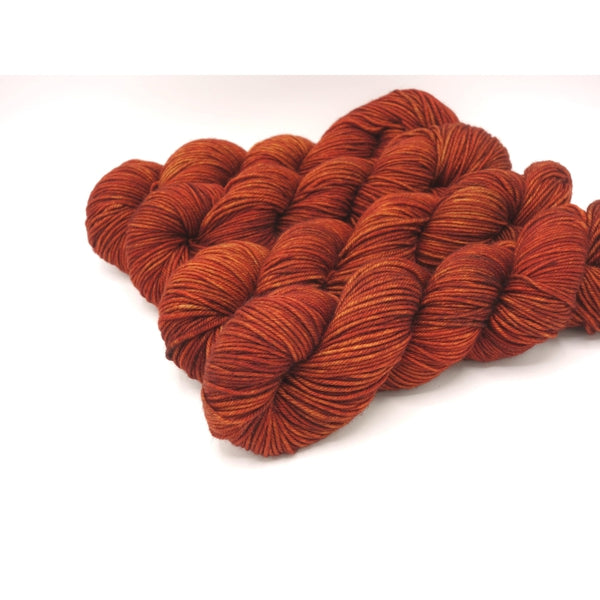 Skeins of Murky Depths Neptune DK Picante, a tonal yarn in deep reddish orange. 