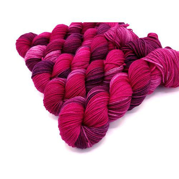 Skeins of Murky Depths Neptune DK Tell Tale Heart, a variegated yarn in shades of fuschia, magenta and deep violet.